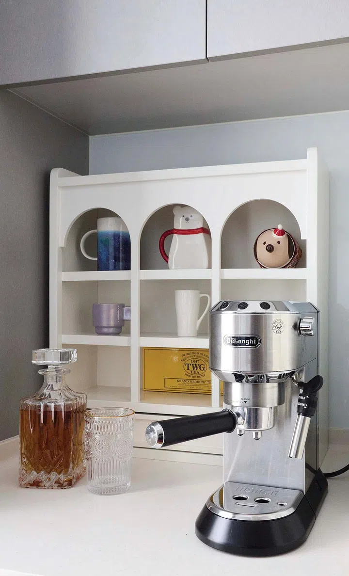 A coffee machine and liquor sits on a countertop Living room in interior designer Vivian Chen (of Muwu Construction) and financial advisor husband, Michael Chan's 635 sq ft 2-bedroom condominium along Stirling Road.