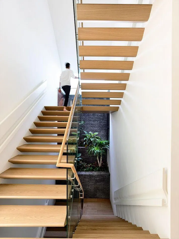 The staircase is a cantilevered structure with a triangular section facing a tiered landscape wall.

