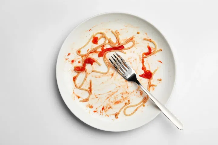 Dirty plate with food leftovers and fork on white background, top view. Photo from 123RF