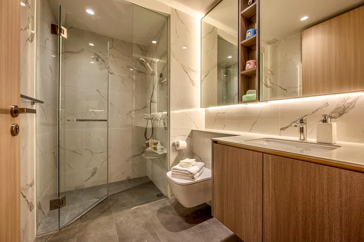 Marble-look finishes and concealed storage give the common bathroom a bright, hotel-inspired feel.