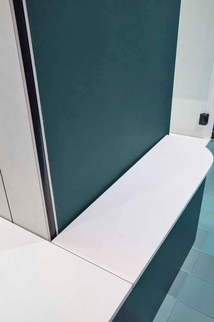 A minimalist bench with green cushions that doubles as storage in the entry and dining area.