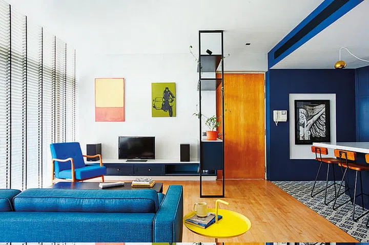 The dark blue shade of the kitchen area complements the warm tones of the living room, which was left in its original state.
