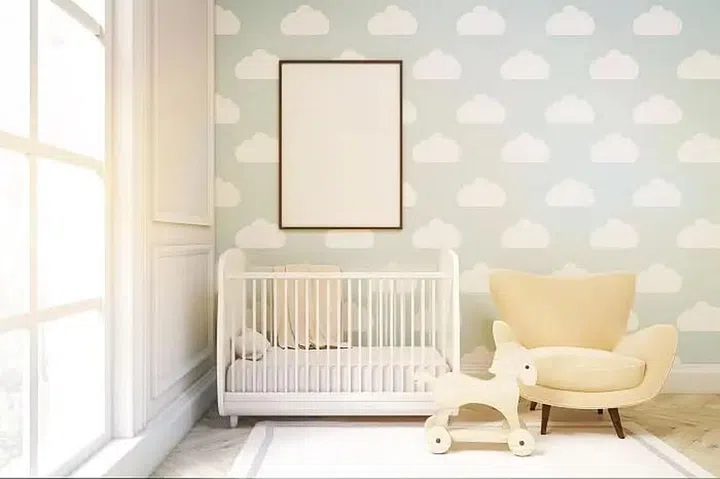 All white with baby blue wallpaper baby nursery room with a cream armchair and white baby cot. Photo 123RF