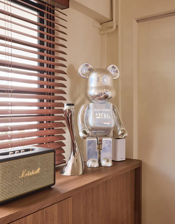 Polished metal accents, from the silver Bearbrick to sculptural lighting, contrast against the warmth of wood and leather for a balanced play of textures.