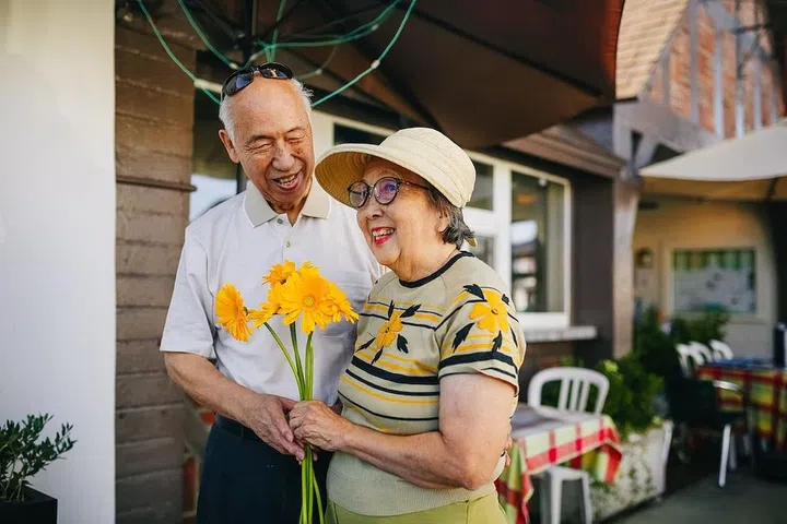 Two elderly holding a bunch of fresh sunflowers