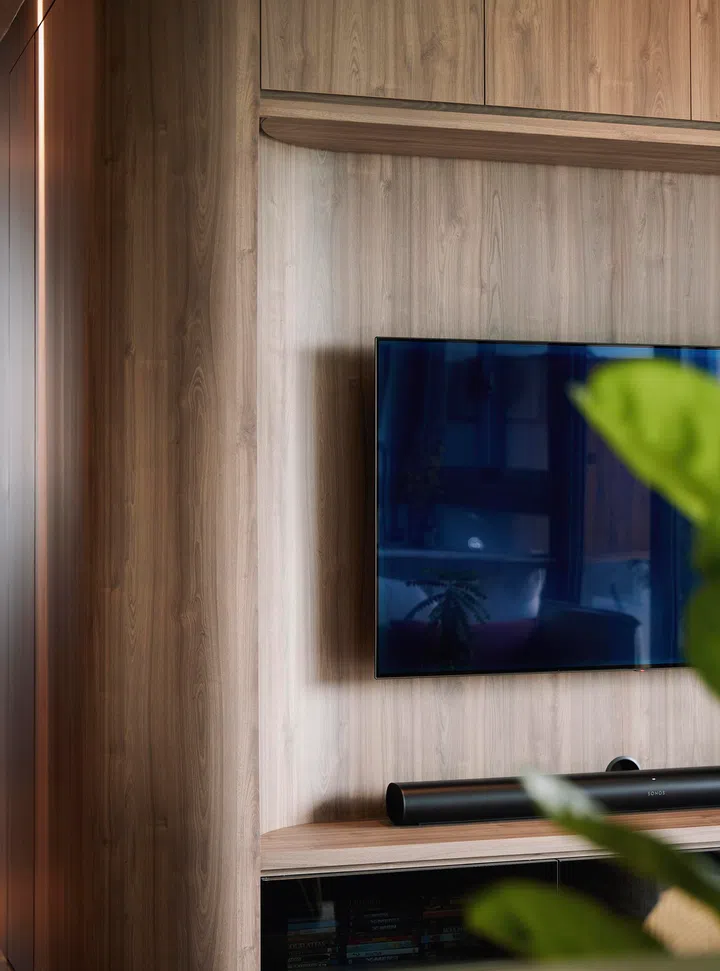 A bespoke curved TV feature wall with flush cabinetry and subtle fluting.
