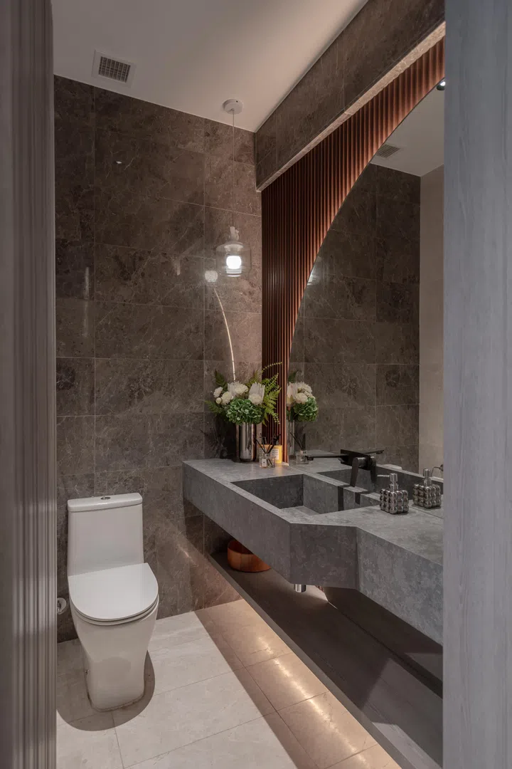 The powder room carries the same sense of considered luxury, with dark stone-look surfaces, warm lighting, and sculptural detailing.