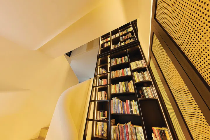 A towering, double-volume book shelf in a 3-bedroom condo (1,800 sq ft) in Pandan Valley, designed by Insight.Out Studio.