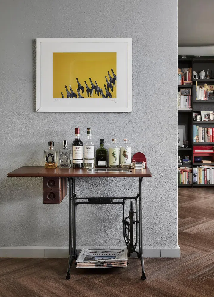 BoConcept bookshelf in the background, vintage sewing table repurposed as a console with collection of liquor bottles on display in this 1,650 sq ft 3-bedroom Marine Parade condo.