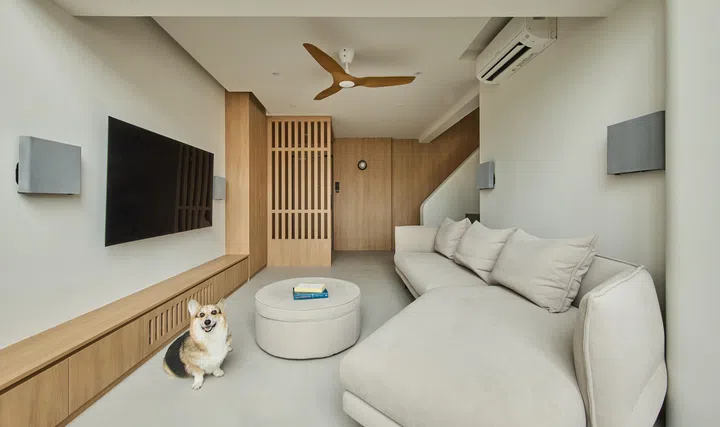 Open plan living room with a hexagon-shaped sofa and built-in storage below the TV. 