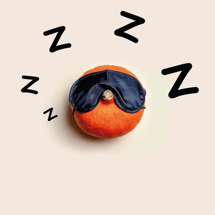 The orange pumpkin sleeps in a sleeping bandage on a light background. Halloween concept