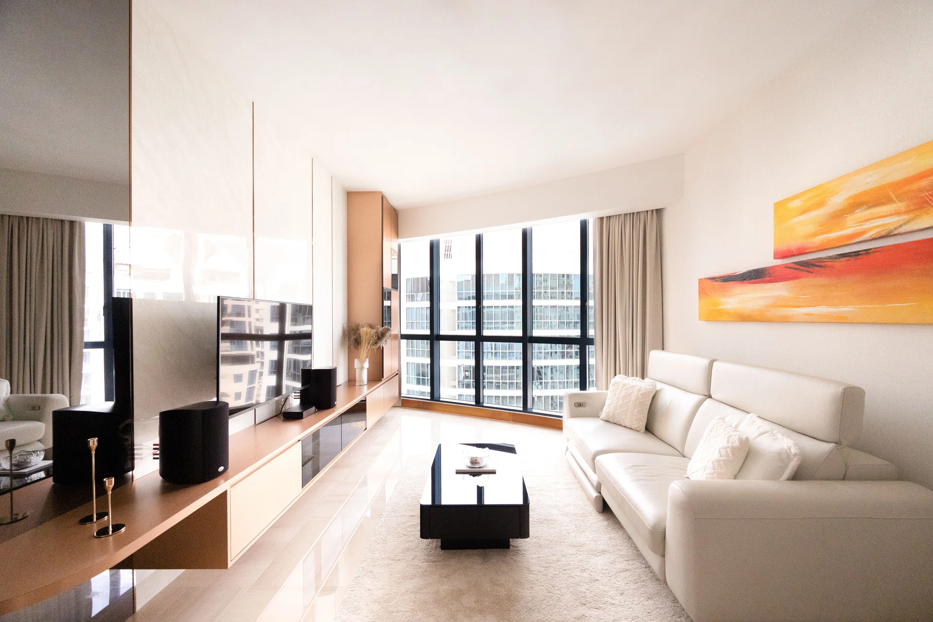 The living room is basked in natural lighting. A shelf with copper-esque accents is built to cushion against the sharp corner there. 