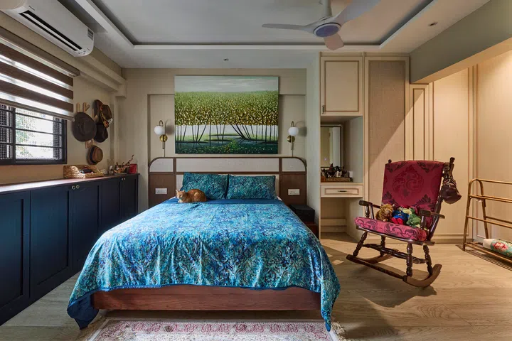 The master bedroom, softened with wood accents, a landscape painting, and a vintage red rocking chair in a 4-room HDB resale in Sunset Way.