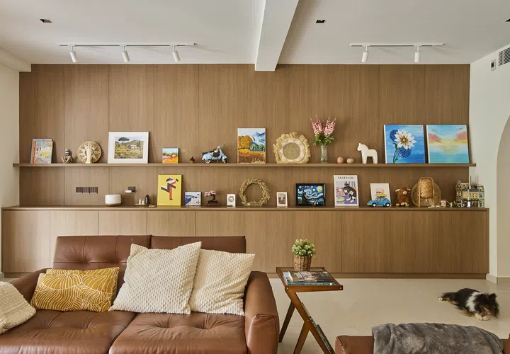 A continuous timber wall with a long display ledge allows the space to evolve over time, with artworks and keepsakes arranged informally against a muted backdrop.