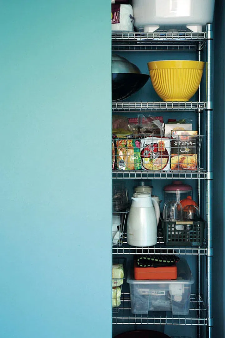 Jermaine created a pantry and storage by installing vibrant turquoise sliding doors and stainless steel racks into an odd niche in the kitchen.