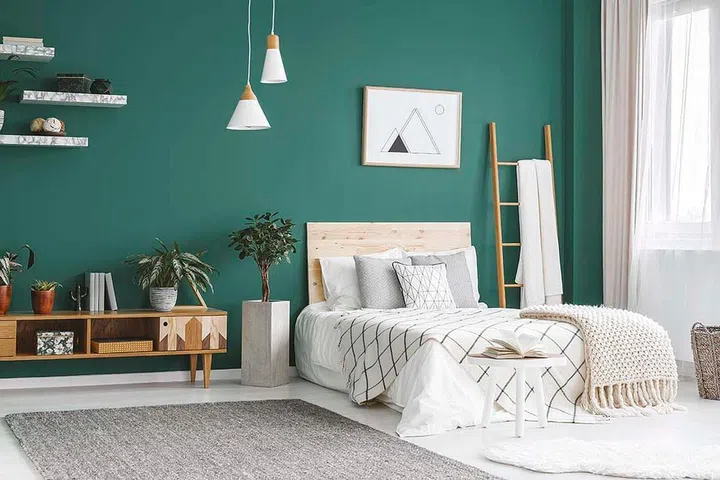 Bed between ladder and plant in green boho bedroom interior with grey carpet under lamps