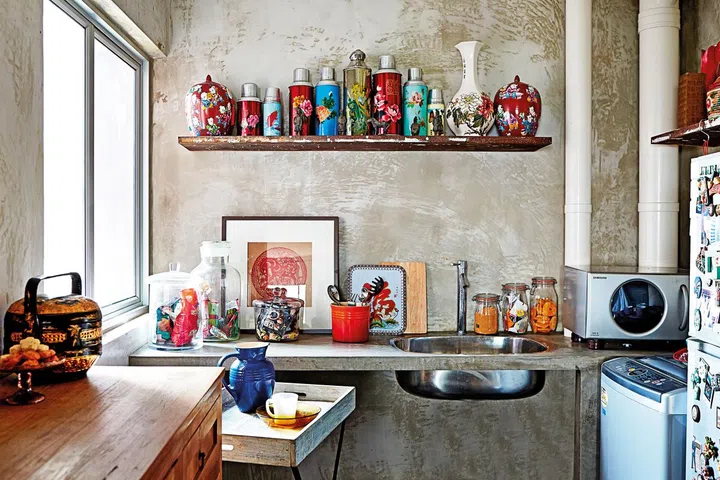 Retro kitchen with old fashioned oriental flasks, vases, and baskets that contrast strikingly against the concrete wall.