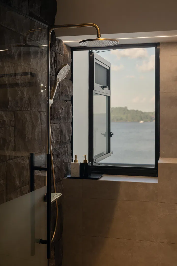 A window view of Pulau Ubin reinforces the home’s resort mood, connecting the bathroom to the surrounding landscape.