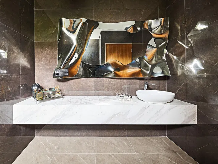 Gracing the wall of the powder room is an eye-catching Christine mirror by Fiam. Its irregular frame creates an interesting play of light and reflections.