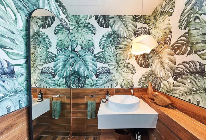 This bathroom’s timber-effect tiles are perfect with the exuberant Green Monstera wallpaper from Hello Circus.
