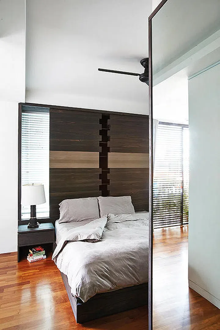 The bay window space in the master bedroom is utilised by installing concealed storage shelving that doubles as the headboard.