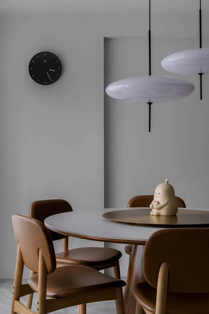 A pared-back dining table sits under a sculptural pendant, keeping the look minimalist yet distinctive.