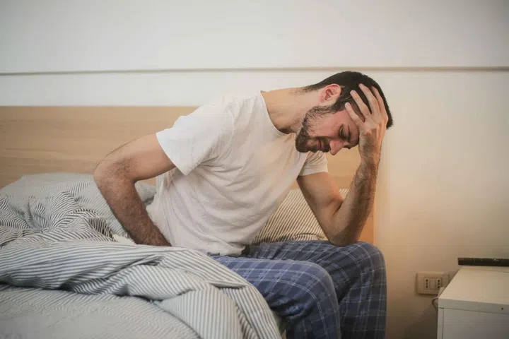 How to Sleep Better? Ear Nose Throat Doctor shares expert tips. Man in pyjamas sitting at bedside, frustrated