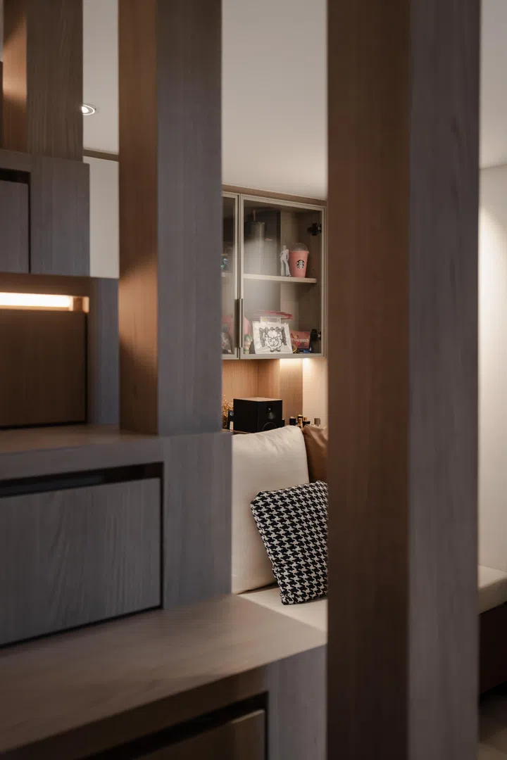 Integrated shelving, concealed storage, and warm lighting help the compact room feel personal rather than crowded.