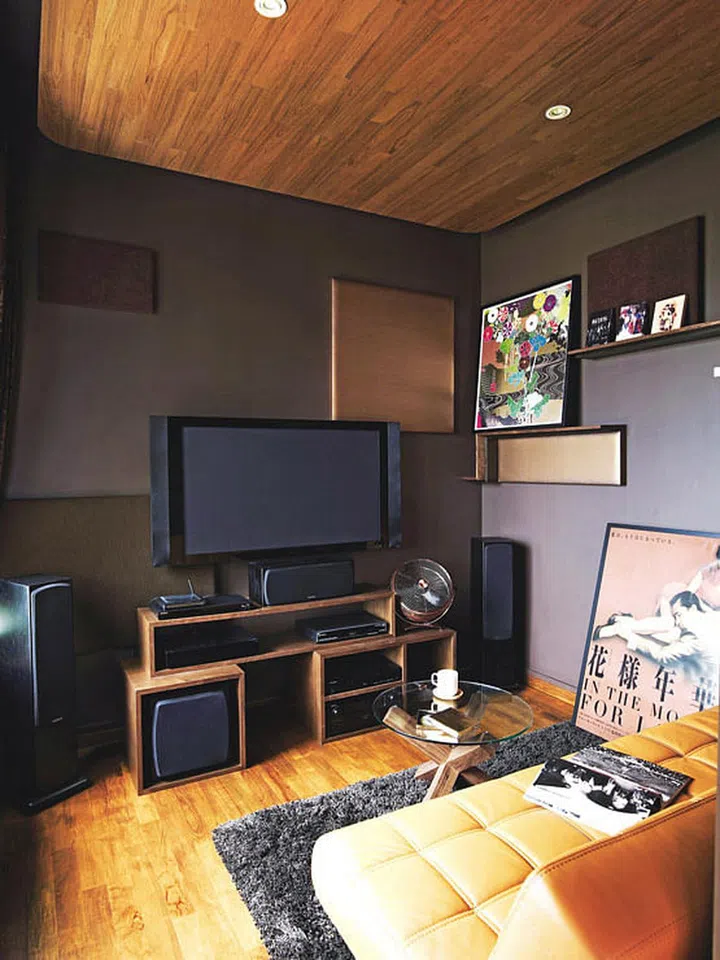 The chocolate-hued entertainment room in this bachelor's modern condominium in Novena is cosy with a thick-pile rug and a veneered false ceiling that mirrors the parquet floor.