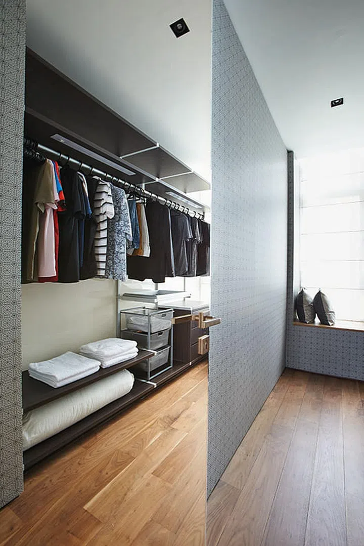 An assortment of racks and shelves in the walk-in cabinet provides ample storage for clothes and accessories in William Png's white and wood 3-bedroom condominium off Orchard Road.