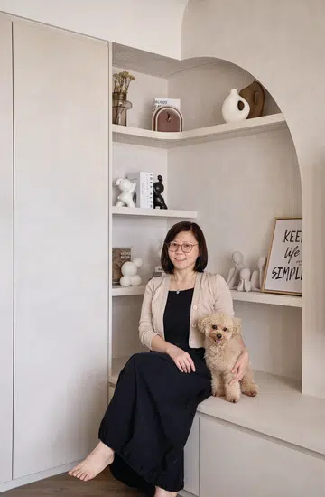 Stephanie Gan sits in the softly lit foyer of her Toa Payoh East flat, where curved flooring and a limewash-effect cabinet wall introduce the home’s warm, inviting aesthetic.