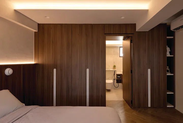 A concealed door merges seamlessly with the surrounding cabinetry, maintaining the clean lines of the bedroom.