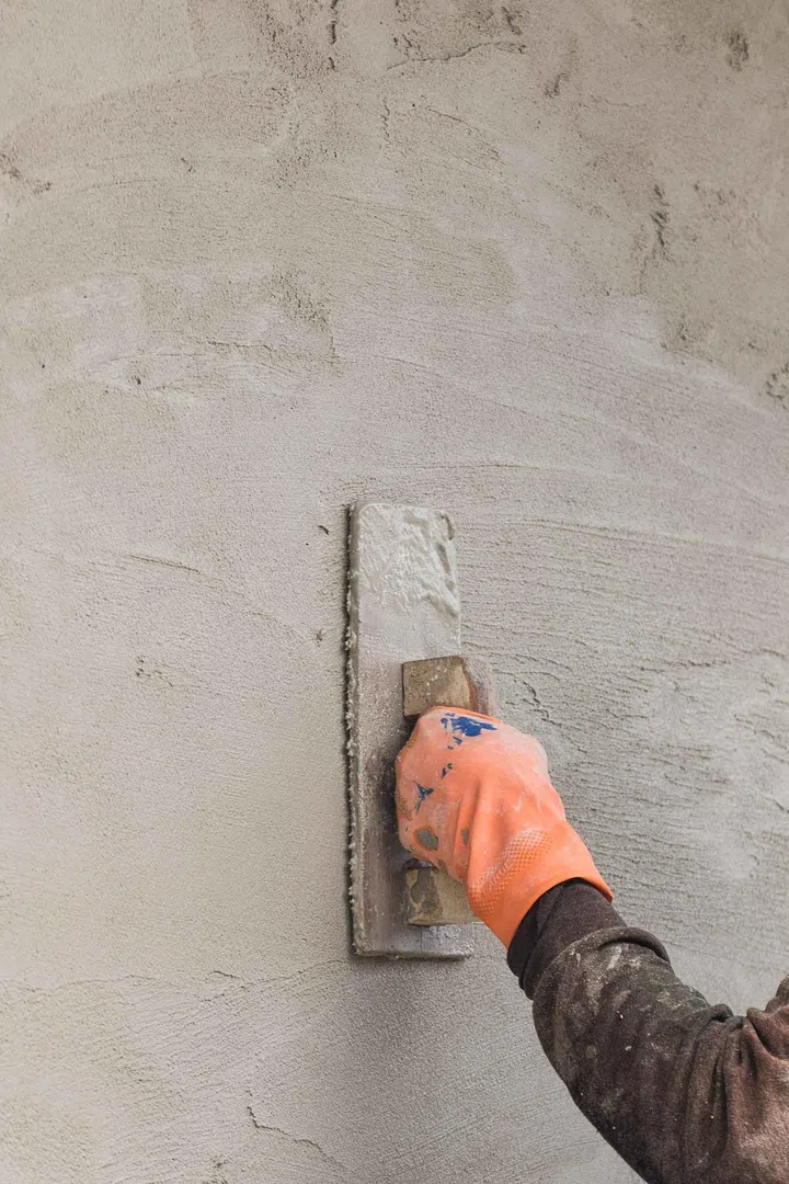 Builder worker plastering concrete at wall of house construction. Image from 123RF