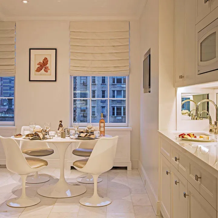 The kitchen incorporates a small dining area with an iconic Eero Saarinen Tulip table with a custom top in a honed Afyon marble. The chair seats are upholstered in a metallic leather from Kravet.