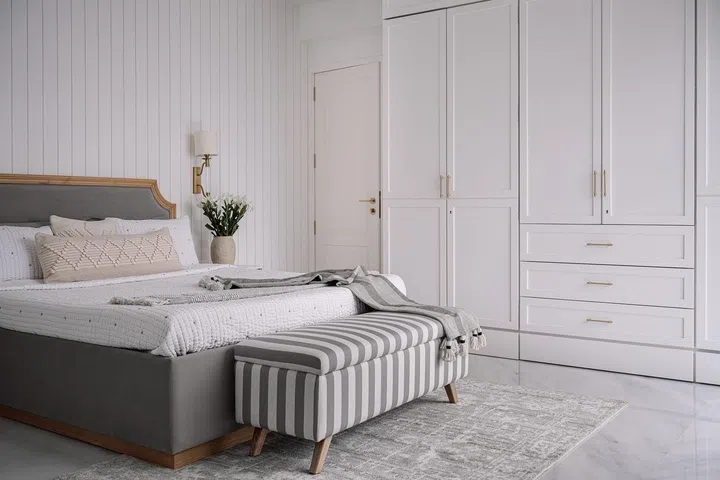 White Shaker-style wardrobe cabinets in the master bedroom for this 2-bedroom apartment in Parsi, Mumbai.