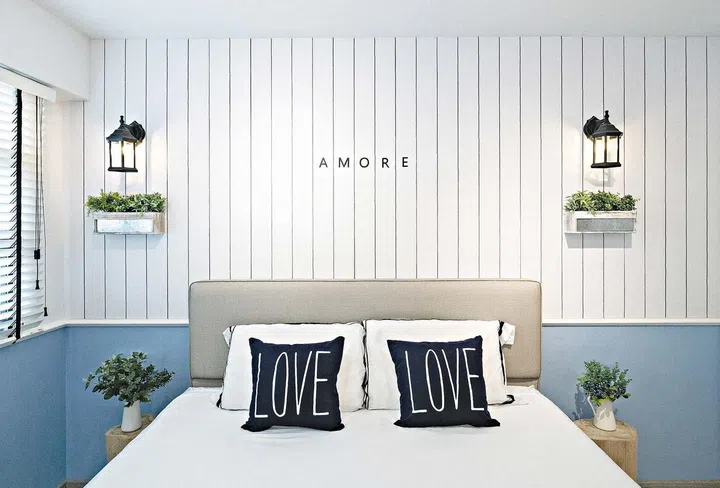 Symmetry is a significant element of the bedroom design, with matching decorative touches like the planters and lights on the wall. The vertical shiplap effect on the walls and wardrobe brings a coastal feel throughout the home.