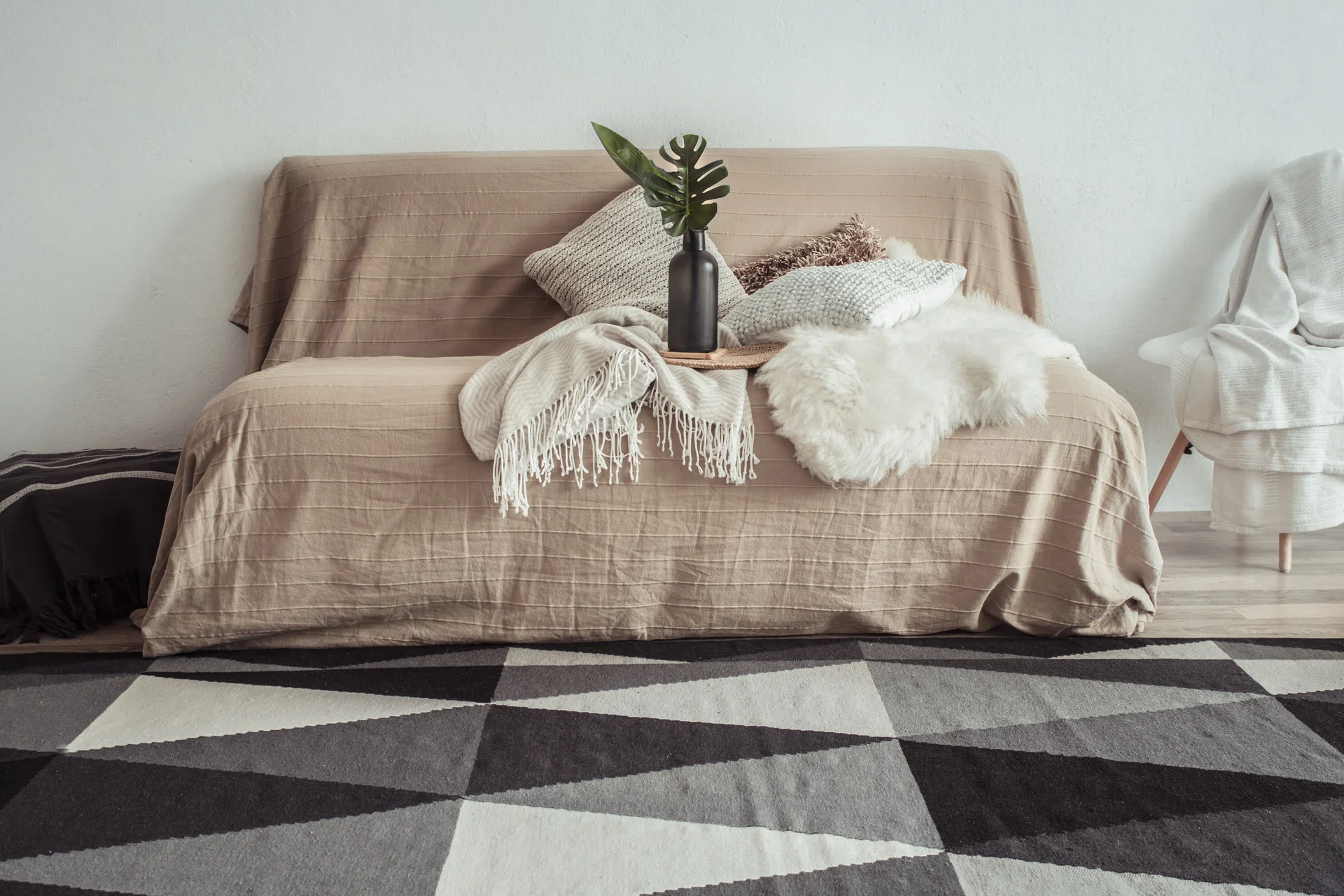 Modern interior of the living room with a sofa and decorative items. Decorative pillows and blankets. Coziness and comfort at home.