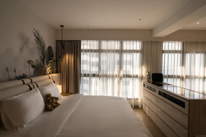 Natural light filters through sheer curtains, illuminating the king-sized bed and tropical mural that set the tone for the home’s resort-inspired calm.