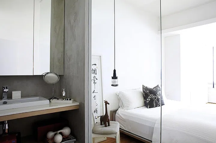 A glass wall separates the master bedroom and the bathroom, allowing light to flood into both spaces. Interior designer by The Interarch Design
