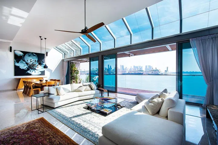 When seated on the plush sofa in the living area, one can indulge in a panoramic view of the vast ocean through the floor-to-ceiling glass doors that seamlessly blend the indoors with the outdoors.