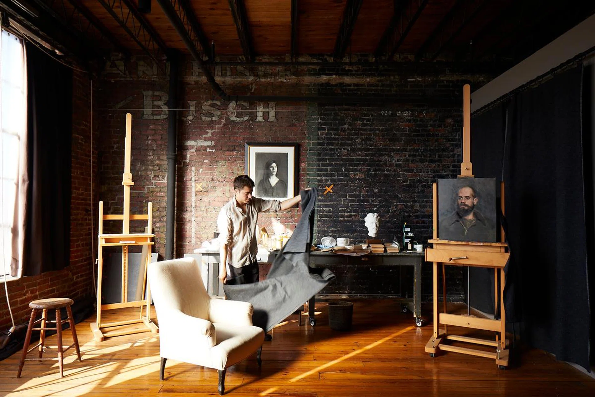 Young artist William Rushton posing with an easle in his creative studio and home, a historic loft with architectural character in a 1918 warehouse in downtown Birmingham, Alabama, restored by architect Paul Bates. Photo by Brie Williams