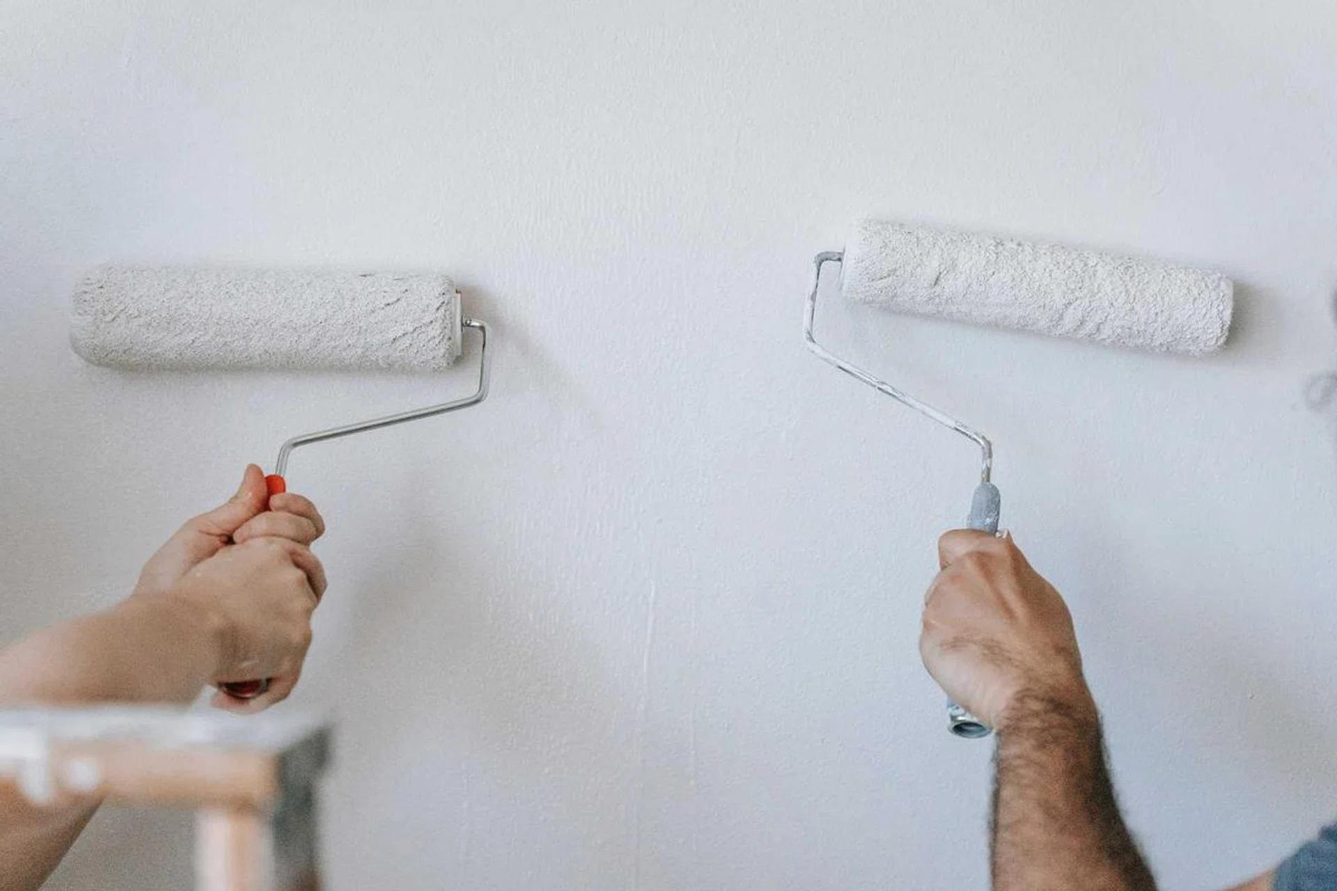 Two persons painting a white wall