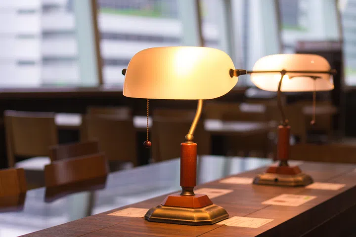 In a quiet corner of a modern coffee shop, elegant vintage lamps cast a warm glow over polished wooden tables.