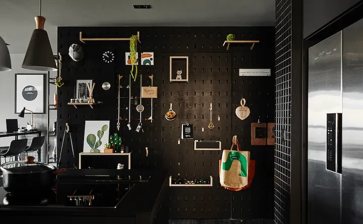 All black kitchen with a full-height black pegboard holding kitchen accessories neatly.