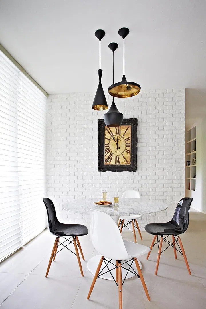 The whitewashed brick wall was retained to help demarcate the dining area from the rest of the open-concept living space. The quirky framed clock lends added emphasis.