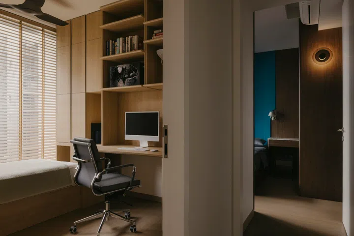 The guest room doubles as Walter’s workspace, with built-in timber shelving framing a compact desk and display ledges.