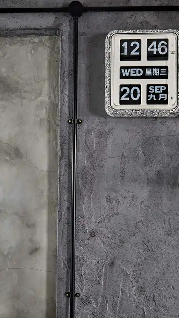 A graphic, retro wall clock set against a textured cement screed wall in flight attendant Kenny Shoo’s 3-room HDB flat at Tampines Street 41.