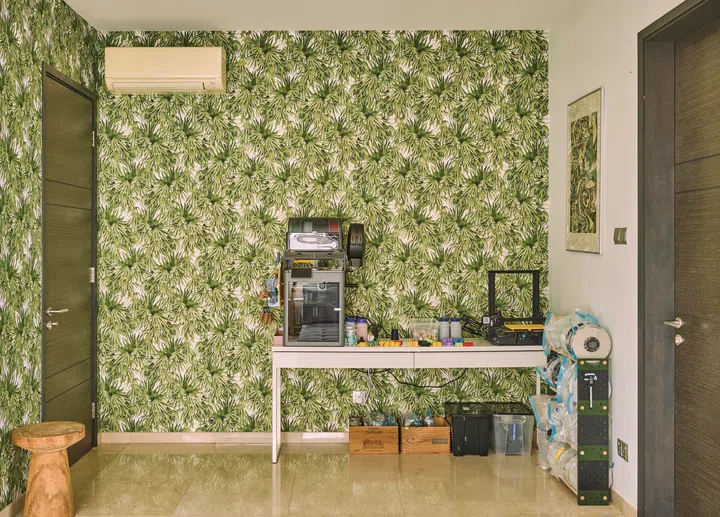The guest room is decked in a green, tropical wallpaper.