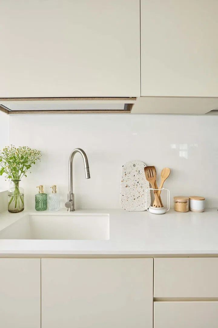 Cream and white kitchen cabinets and sink in a minimalist 5-room HDB BTO in Tampines.