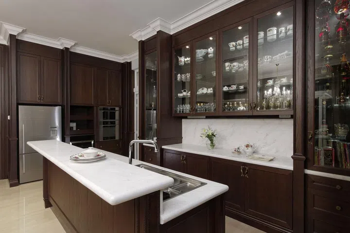 This dark wood kitchen exudes a certain classic charm. Glass-front cabinets showcases homeowner's personal collection of favorite pieces.This dark wood kitchen exudes a certain classic charm. Glass-front cabinets showcases homeowner's personal collection of favorite pieces.